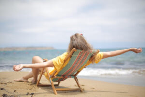 A woman sitting in a chair at the beach.